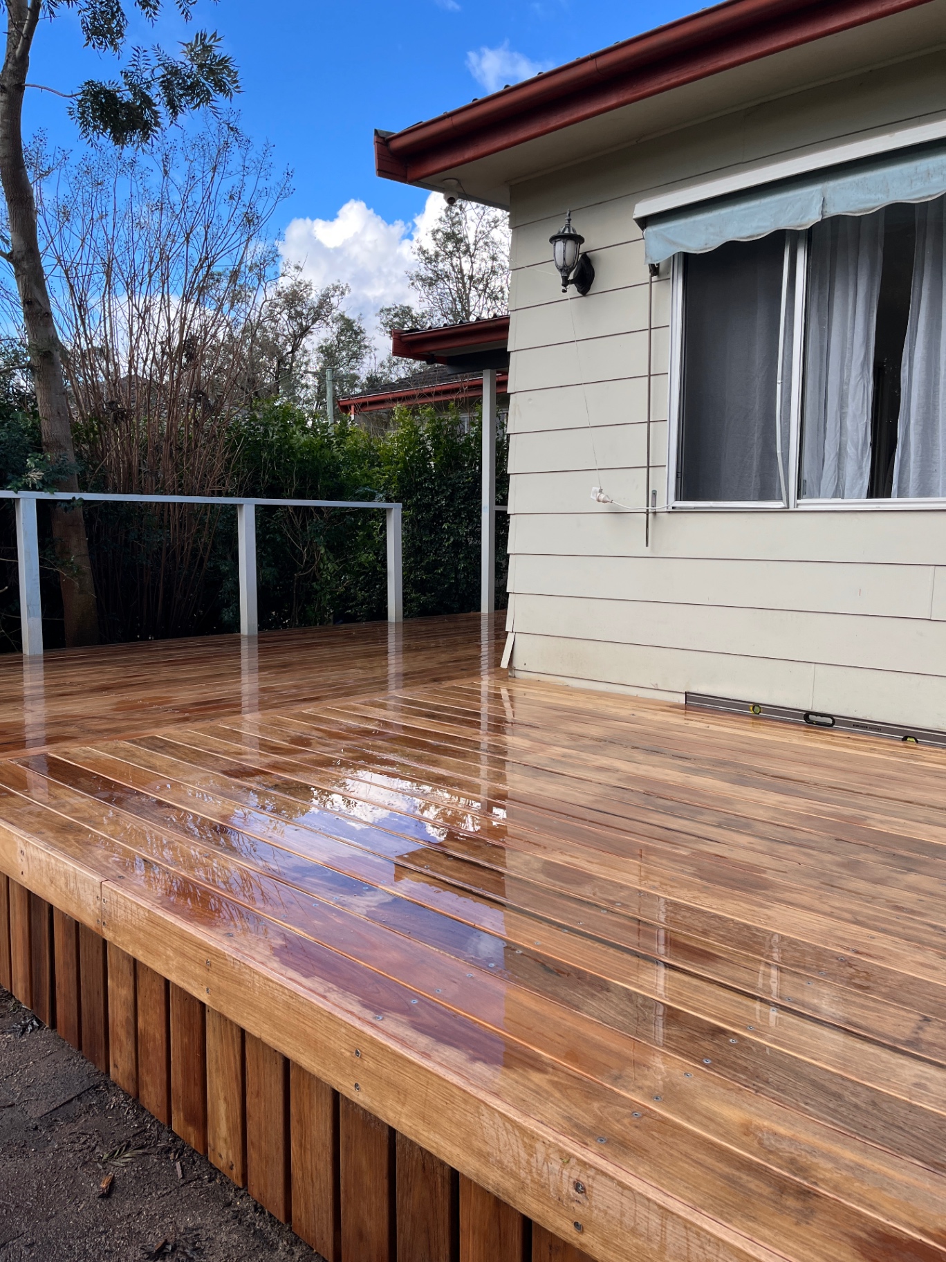 New 140mm tallowood deck wrapping the rear of a weatherboard home at Cessnock after rain
