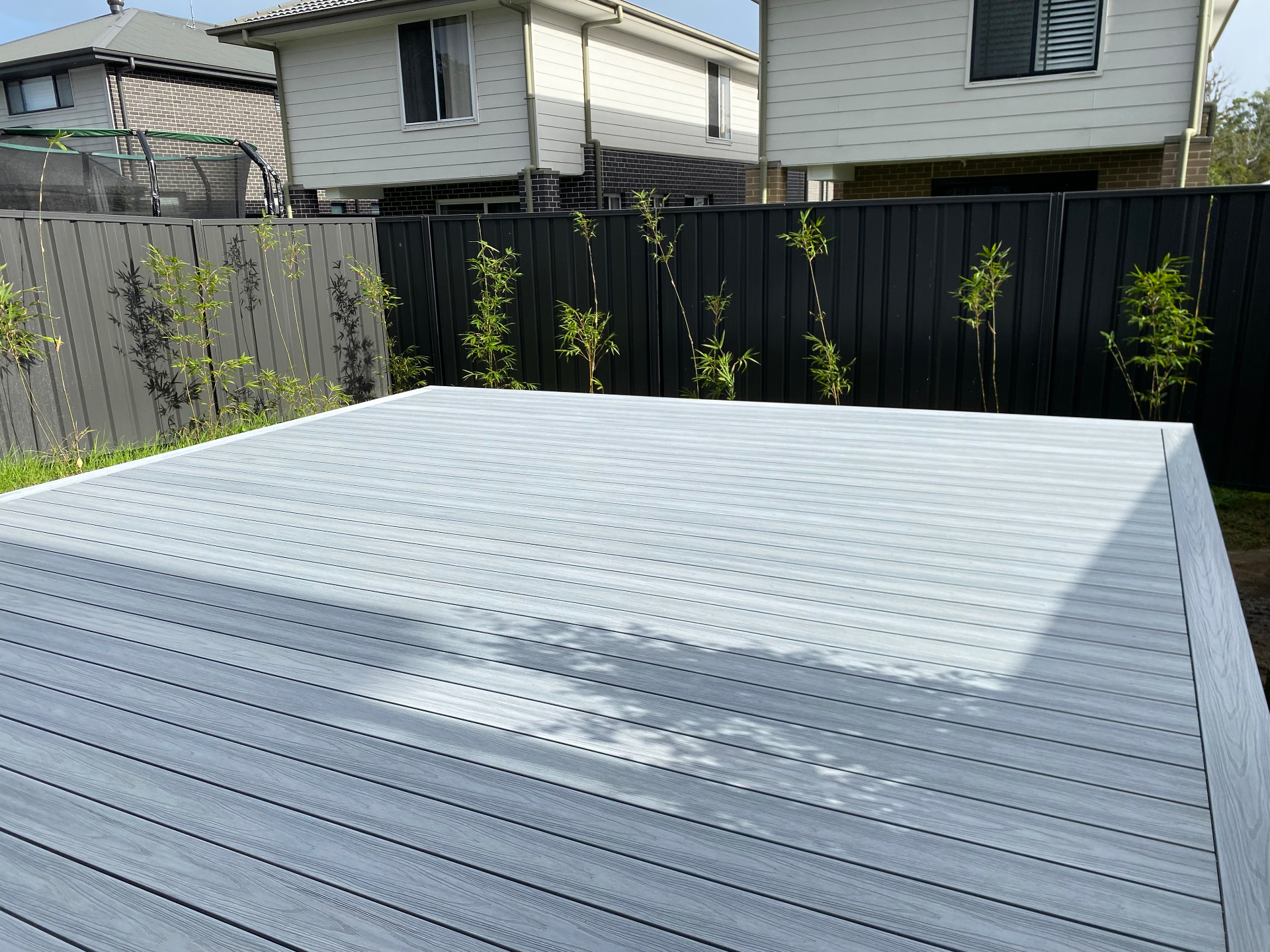 Wide grey Infinity composite entertaining deck in a Warnervale backyard with bamboo screening behind