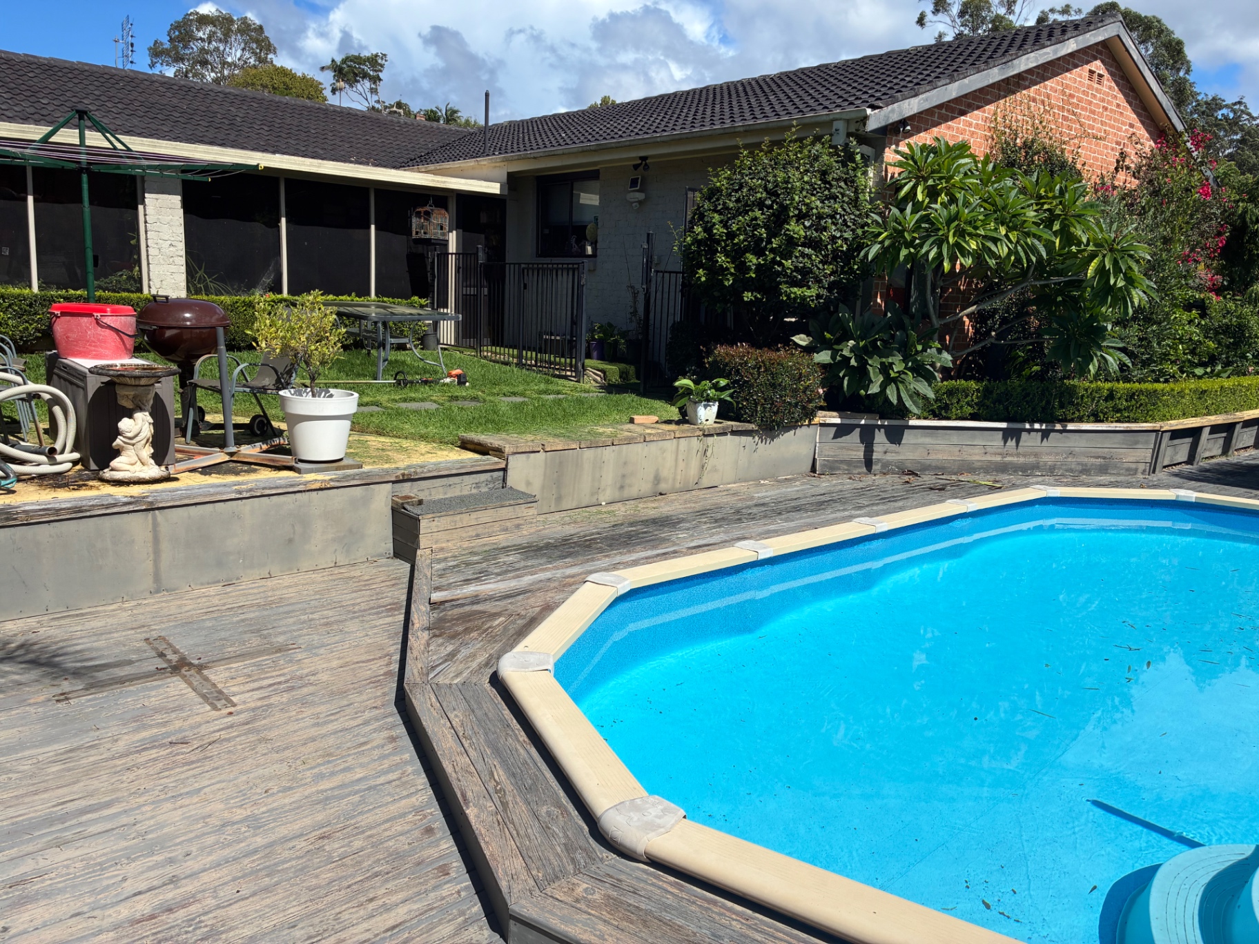 Before: weathered timber pool deck and stepped garden beds at the Green Point property