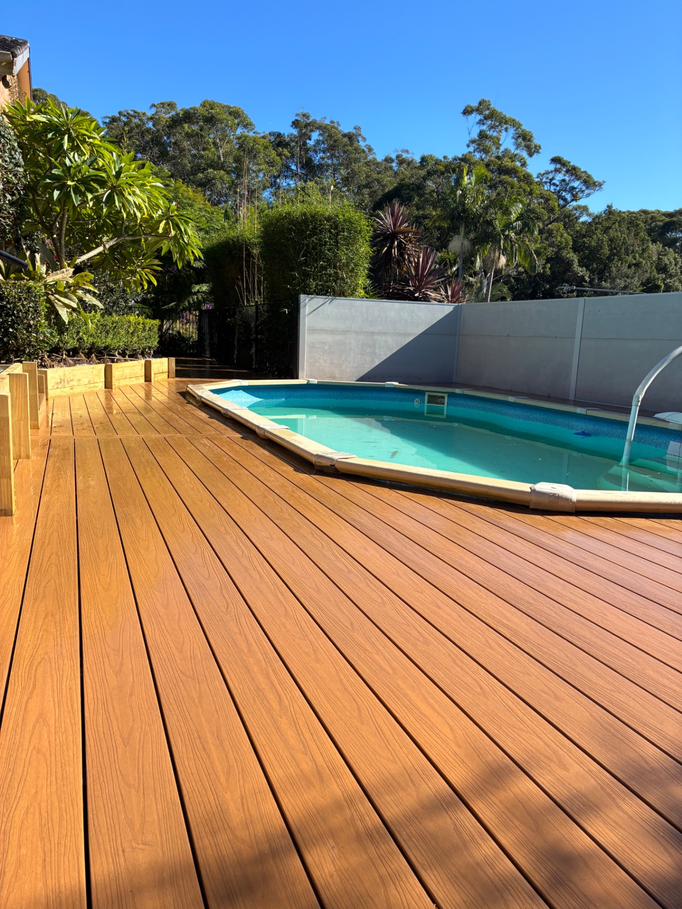 Completed Ekodeck composite poolside deck wrapping an above-ground pool at a Green Point home