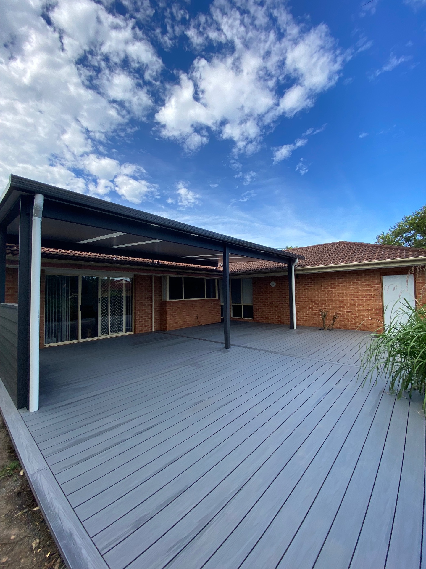 Grey Infinity composite deck under a black insulated panel flyover pergola at a Chittaway Bay home