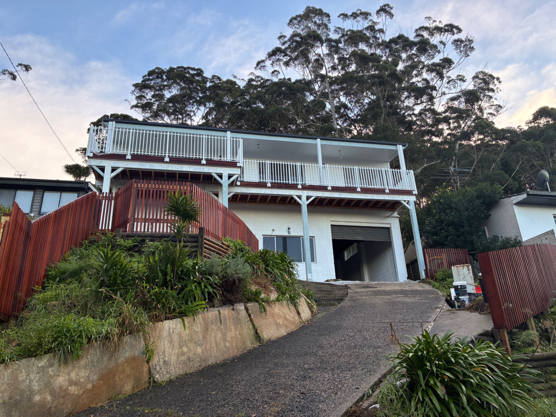 Elevated merbau deck and integrated pergola across the front of a Wamberal home at dusk