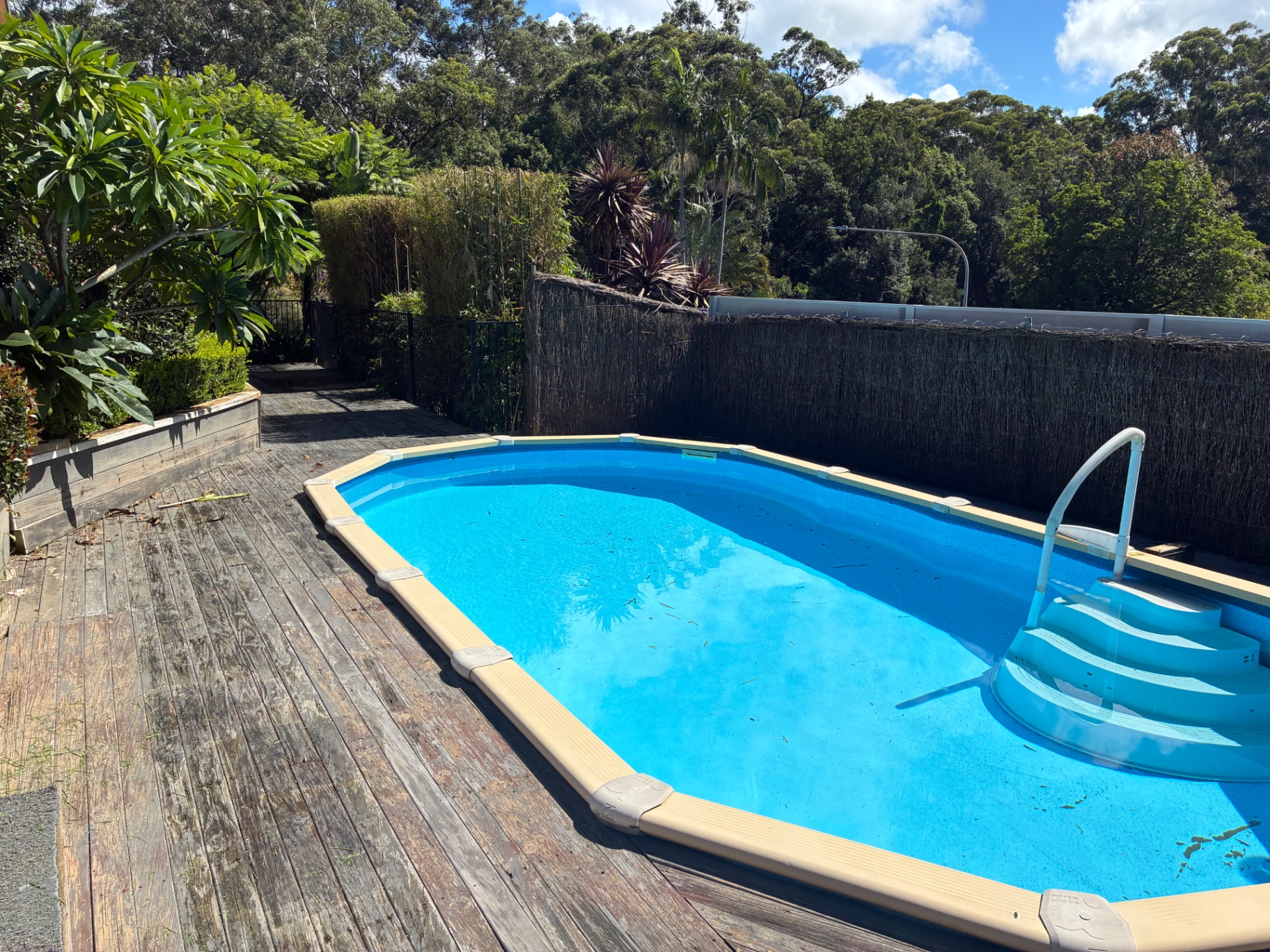 Before: grey, weathered and rotting timber pool deck boards at a Green Point home